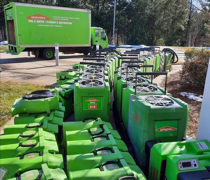 A large lineup of SERVPRO equipment near a large SERVPRO truck, including dehumidifiers and air movers