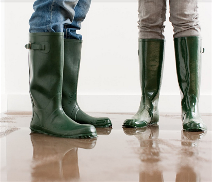 a water logged carpet with two people standing on it in rainboots