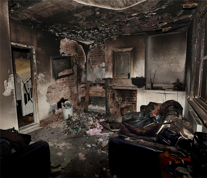a fire damaged living room with debris covering the floor and soot covering the walls